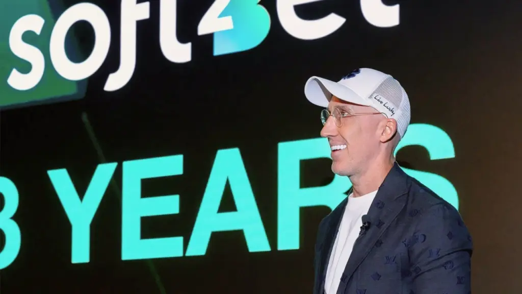Logo Soft2Bet avec portrait d'Uri Poliavich lors d'un événement au Canada